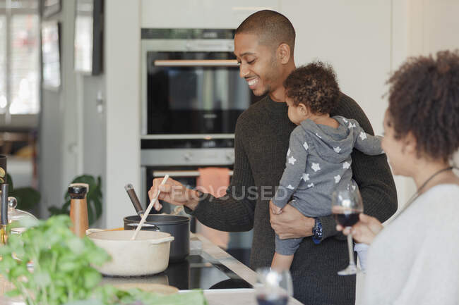 Casal feliz com bebê filha cozinhar jantar na cozinha — Fotografia de Stock