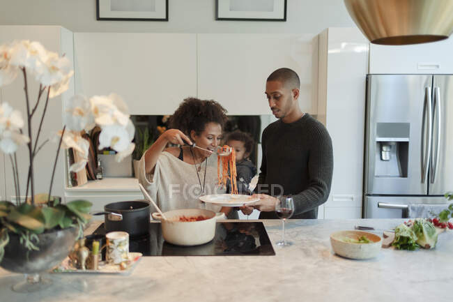 Casal com bebê filha cozinhar espaguete na cozinha — Fotografia de Stock