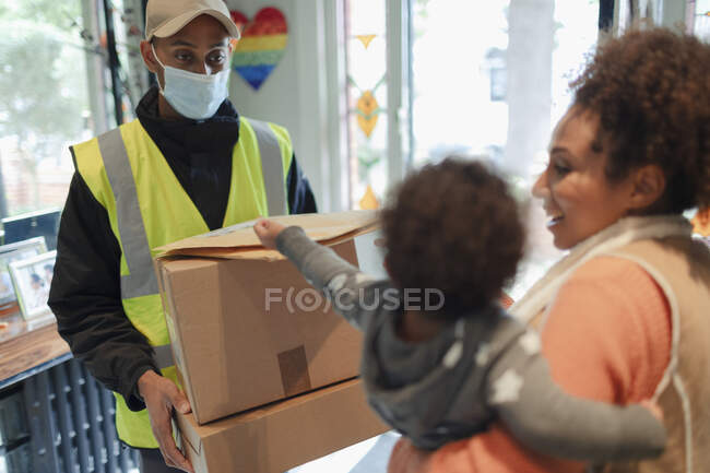 Madre e bambina ricevono i pacchi dall'uomo di consegna in maschera — Foto stock