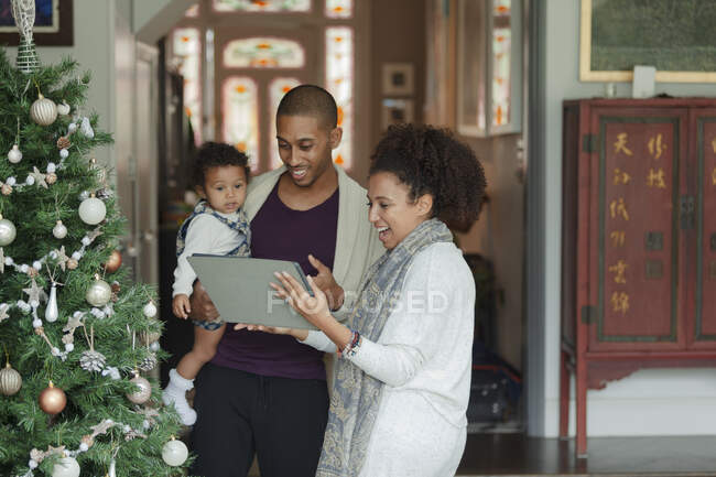 Family video chatting with digital tablet at Christmas tree — Stock Photo