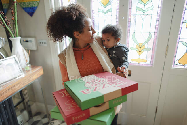 Mãe com bebê filha recebendo entrega de pizza na porta da frente — Fotografia de Stock