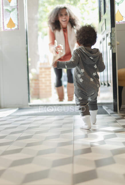 Joyeux bébé fille courir pour saluer la mère à la porte — Photo de stock