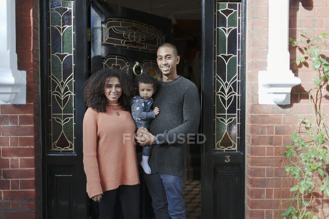 Retrato padres felices con hija bebé en la puerta principal de la casa - foto de stock