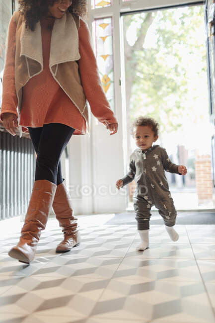Милая маленькая дочка следует за матерью в коридоре входа — стоковое фото