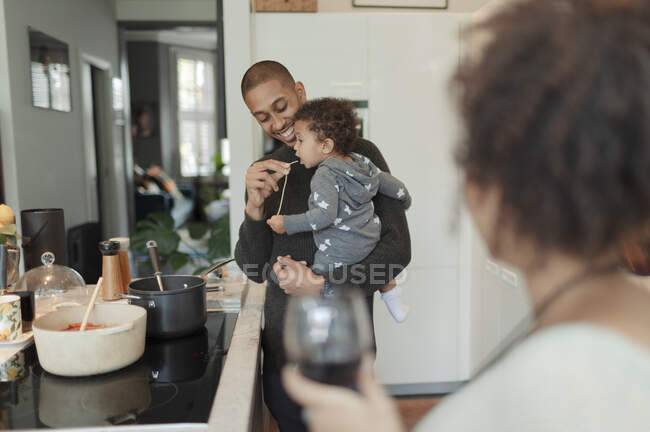 Pai cozinhar e alimentar a filha bebê no fogão da cozinha — Fotografia de Stock