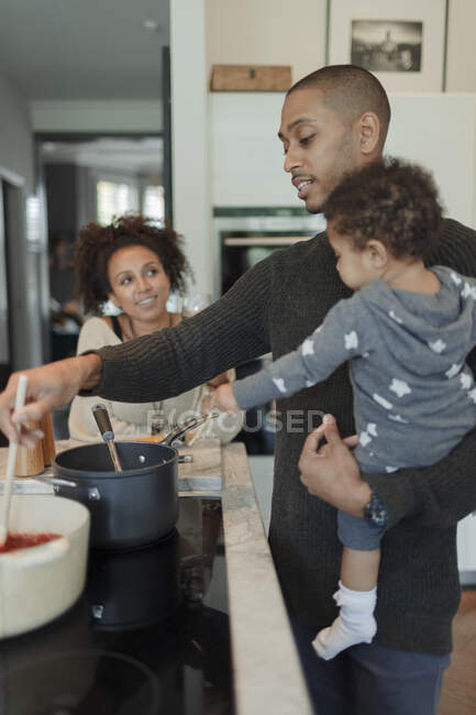 Casal com bebê filha cozinhar no fogão da cozinha — Fotografia de Stock