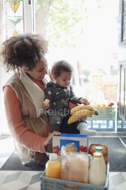 Mère et bébé fille recevant livraison d'épicerie à la porte d'entrée — Photo de stock