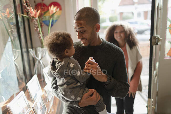 Happy father holding baby daughter at front door — Stock Photo