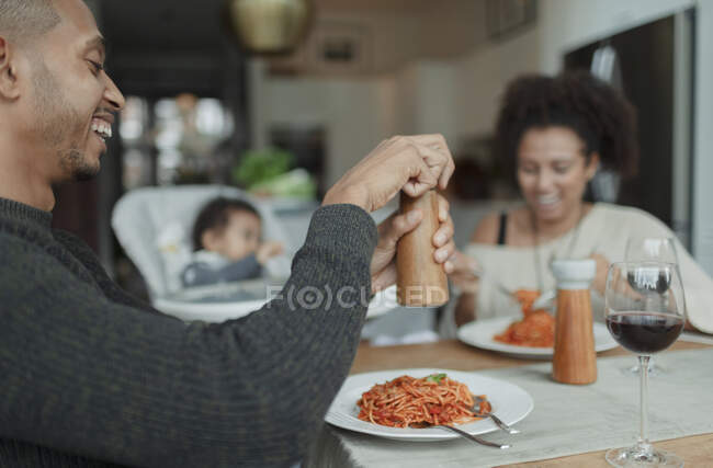 Happy family enjoying spaghetti dinner at dining table — Stock Photo