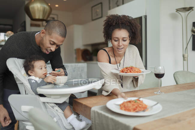 Coppia mangiare spaghetti e nutrire figlia bambino a tavolo da pranzo — Foto stock