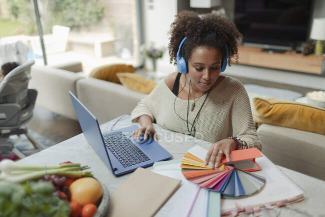 Female designer with color swatches working from home at laptop — Stock Photo