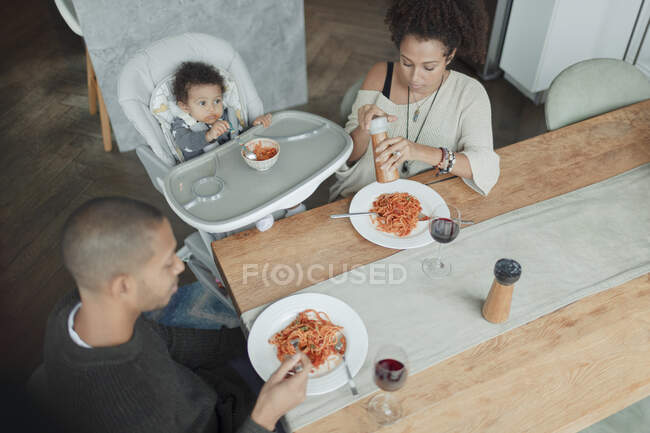 Família comer espaguete na mesa de jantar e cadeira alta — Fotografia de Stock