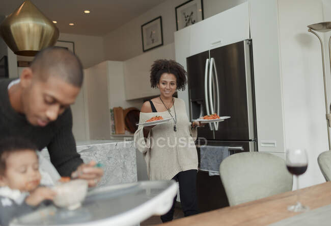 Frau trägt Teller mit Spaghetti auf Esstisch — Stockfoto