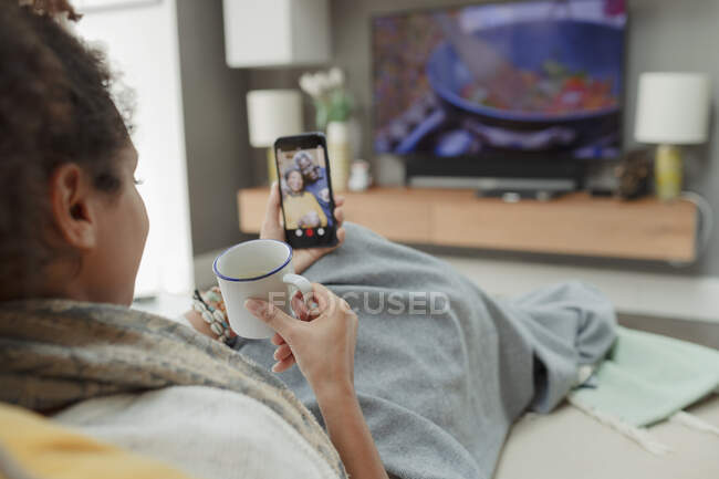 Femme avec thé vidéo bavarder avec les parents sur l'écran de téléphone intelligent — Photo de stock