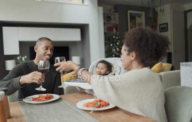 Счастливая пара с дочкой наслаждается вином и ужином со спагетти — стоковое фото