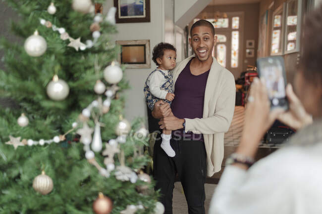Happy father and baby daughter posing for photo by Christmas tree — Stock Photo