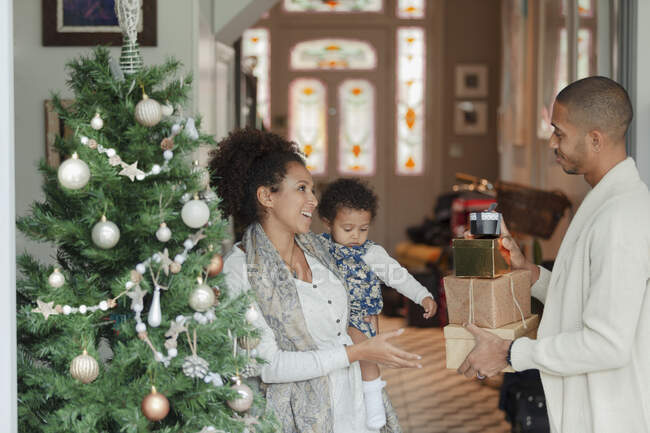 Familia feliz con regalos de Navidad por árbol en la sala de estar - foto de stock