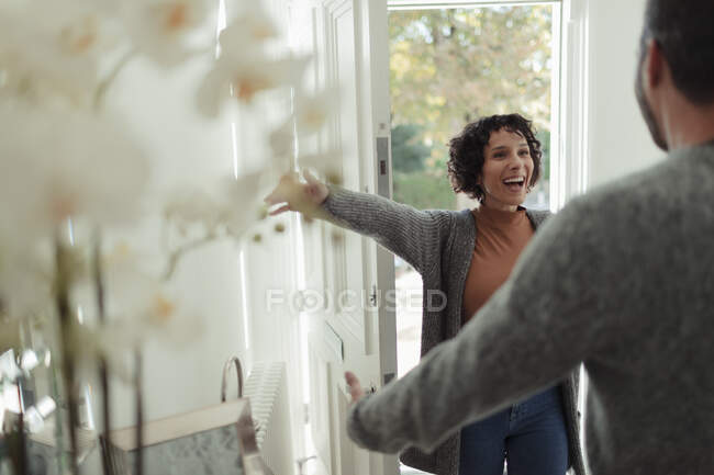 Feliz marido saludo esposa emocionada en la puerta principal - foto de stock