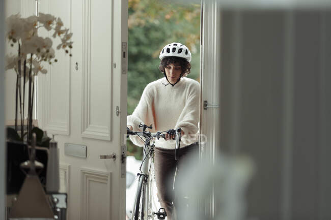 Donna con bicicletta che torna a casa davanti alla porta — Foto stock