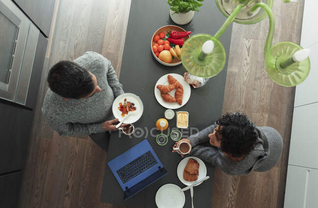 Пара наслаждается завтраком на кухне счетчик с ноутбуком — стоковое фото
