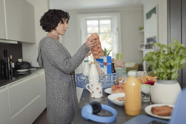 Жінка розвантажує доставку продуктів на кухонній стійці — стокове фото