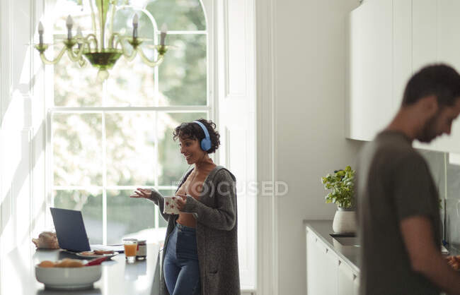 Donna con cuffie videoconferenza al computer portatile in cucina — Foto stock
