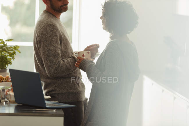 Couple parlant à l'ordinateur portable dans la cuisine du matin — Photo de stock