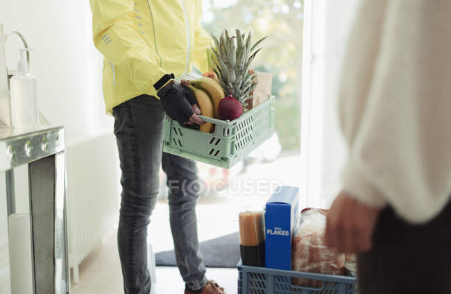 Livreur avec caisses d'épicerie à la porte d'entrée — Photo de stock