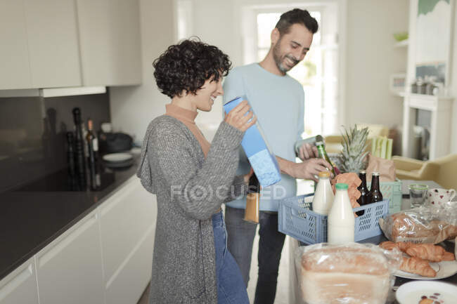 Felice coppia disimballaggio consegna della spesa al bancone della cucina — Foto stock