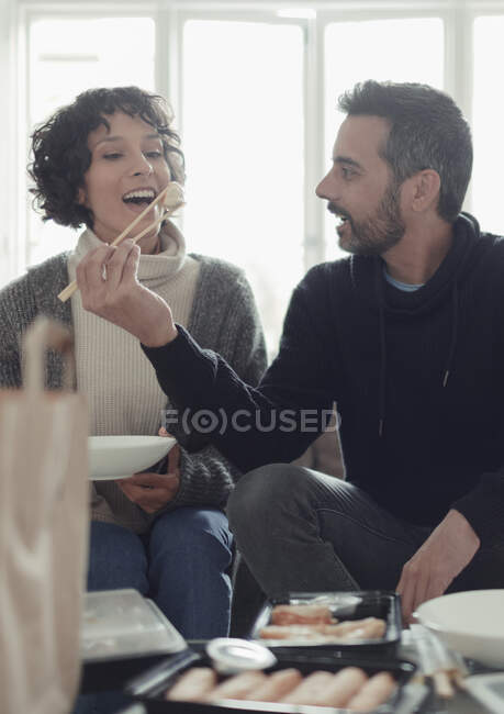 Couple ludique manger de la nourriture à emporter avec des baguettes — Photo de stock