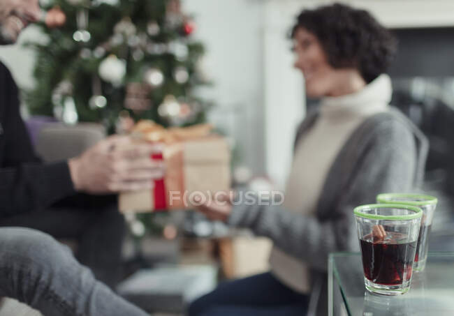 Щаслива пара відкриває різдвяні подарунки у вітальні. — стокове фото