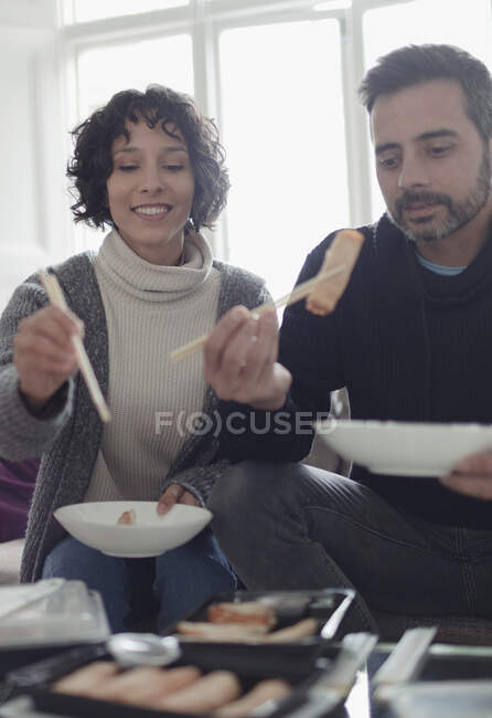 Paar genießt Essen zum Mitnehmen mit Essstäbchen im Wohnzimmer — Stockfoto