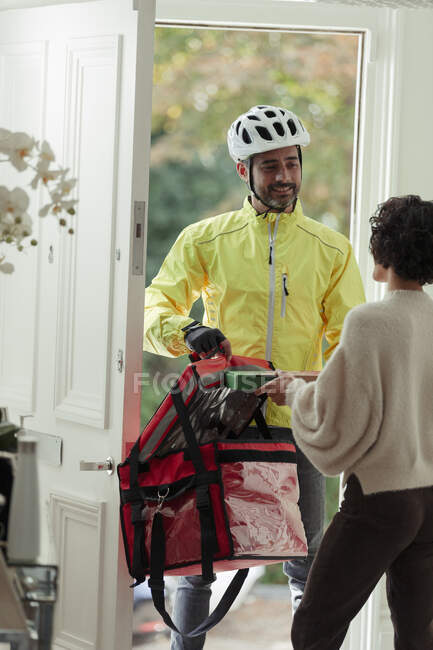 Mujer recibiendo la entrega de pizza del repartidor en la puerta principal - foto de stock