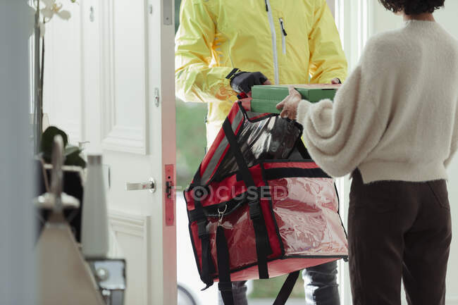 Woman receiving pizza delivery from man at from courier at front door — Stock Photo