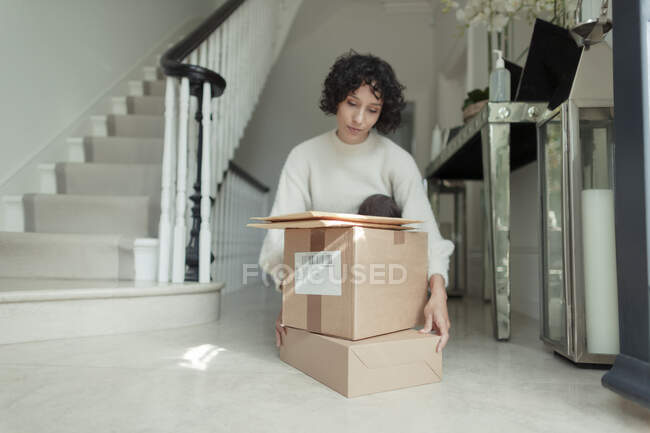 Mulher recebendo pacotes empilhados no piso do foyer — Fotografia de Stock