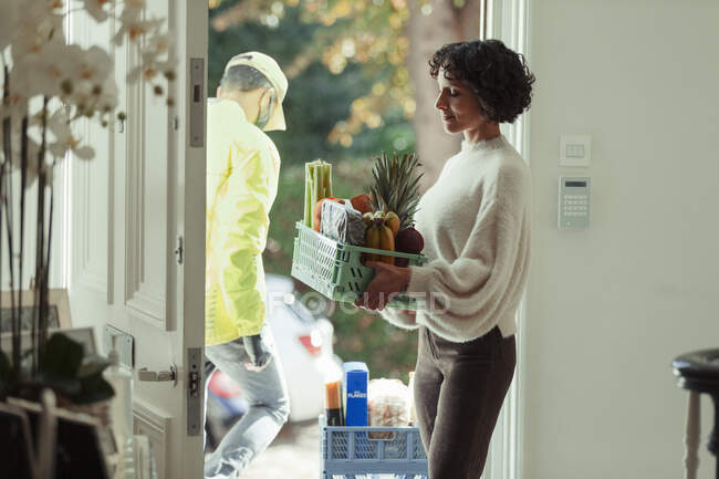 Woman receiving grocery delivery from courier at front door — Stock Photo
