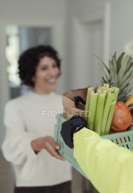 Mujer recibiendo entrega de comestibles de mensajero - foto de stock