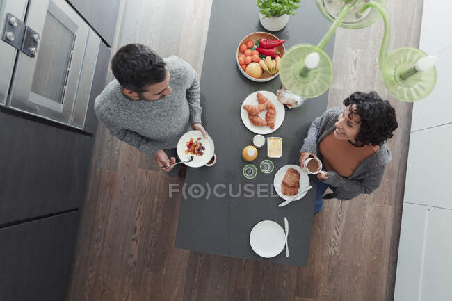 Couple talking and enjoying breakfast at kitchen island — Stock Photo