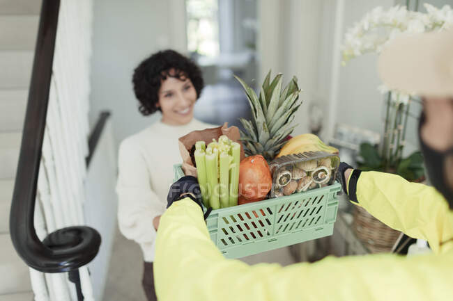 Grateful woman receiving grocery delivery from courier at home — Stock Photo