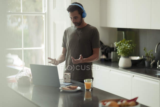 Man with headphones working from home video conferencing at laptop — Stock Photo