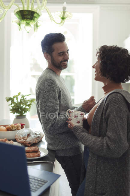 Happy couple talking and drinking coffee in morning kitchen — Stock Photo