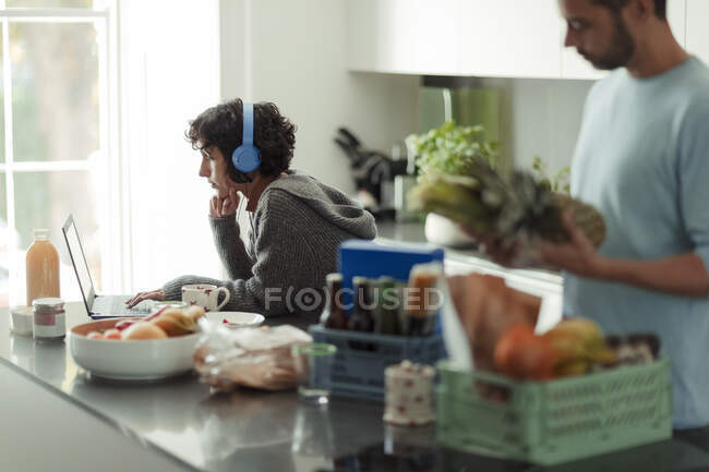 Пара работает из дома и разгружает продукты на кухне — стоковое фото