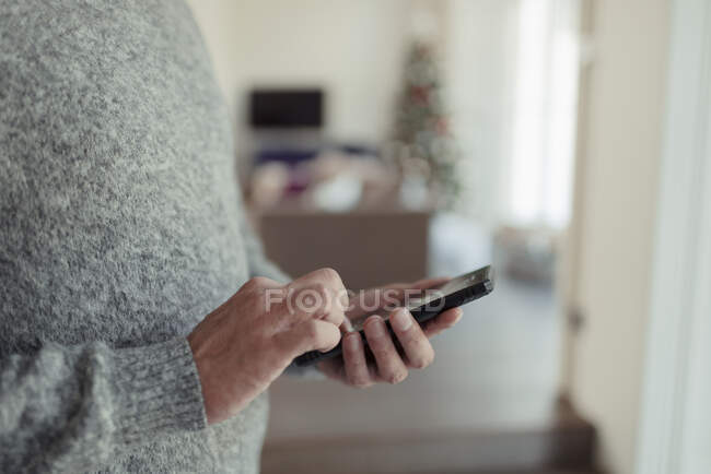 Hombre de cerca en suéter usando el teléfono inteligente - foto de stock
