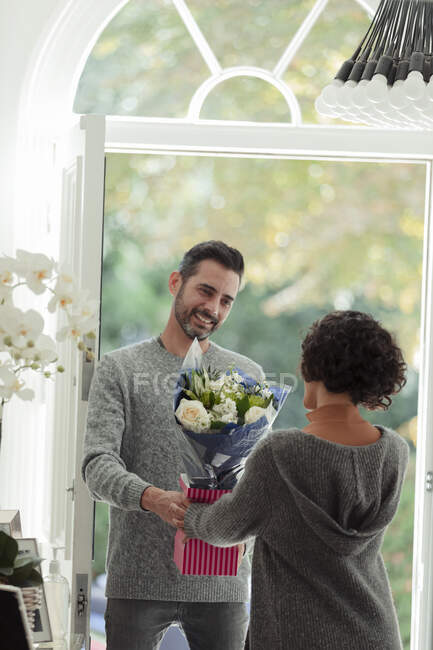 Glücklicher Ehemann überrascht Ehefrau mit Blumen vor der Haustür — Stockfoto