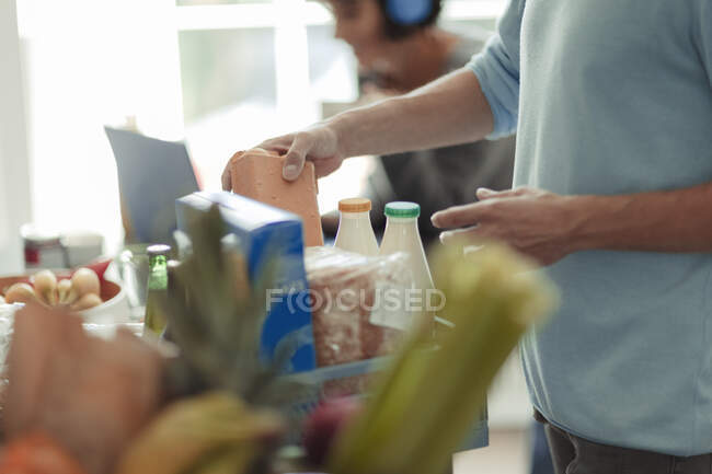 Uomo scarico consegna generi alimentari al bancone della cucina — Foto stock
