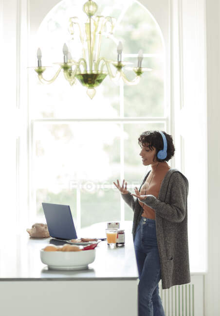 Mulher em fones de ouvido em videochamada trabalhando em casa no laptop — Fotografia de Stock