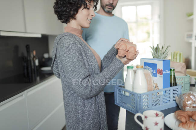 Paar packt Lebensmittel am Küchentisch aus — Stockfoto