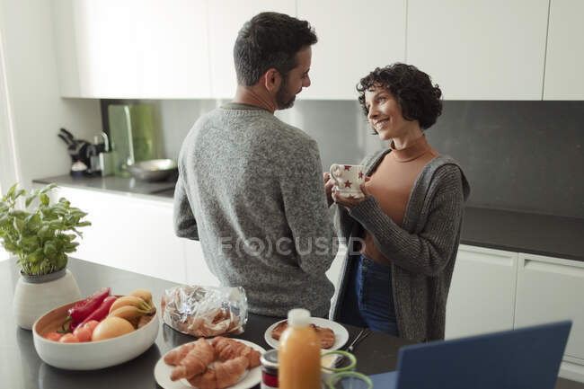 Happy couple enjoying breakfast and coffee in morning kitchen — Stock Photo