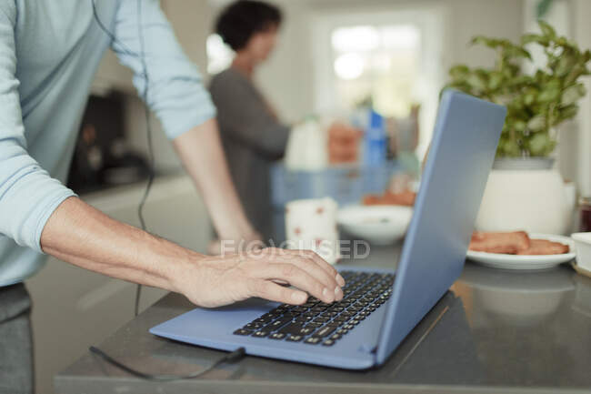 Fechar o homem que trabalha de casa no laptop no balcão da cozinha — Fotografia de Stock