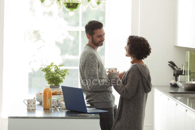 Glückliches Paar spricht und arbeitet morgens in der Küche — Stockfoto